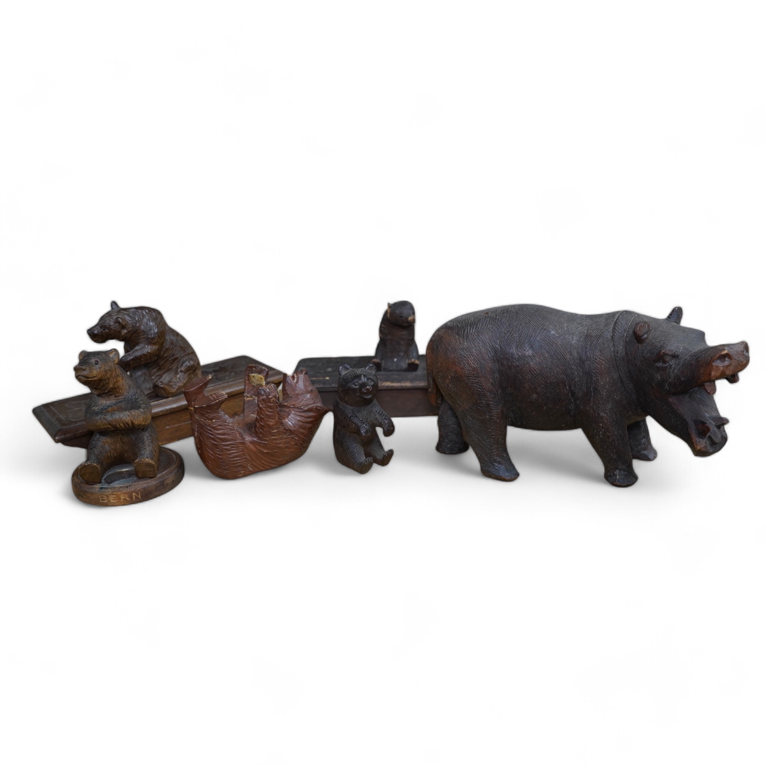 Five carved Black Forest bears, two in the form of ink blotters, together with an African figure of a hippopotamus, largest 17cm wide. Condition - poor to fair
